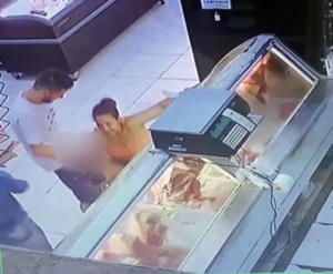 Woman bends to do the unusual on man at meat section of supermarket